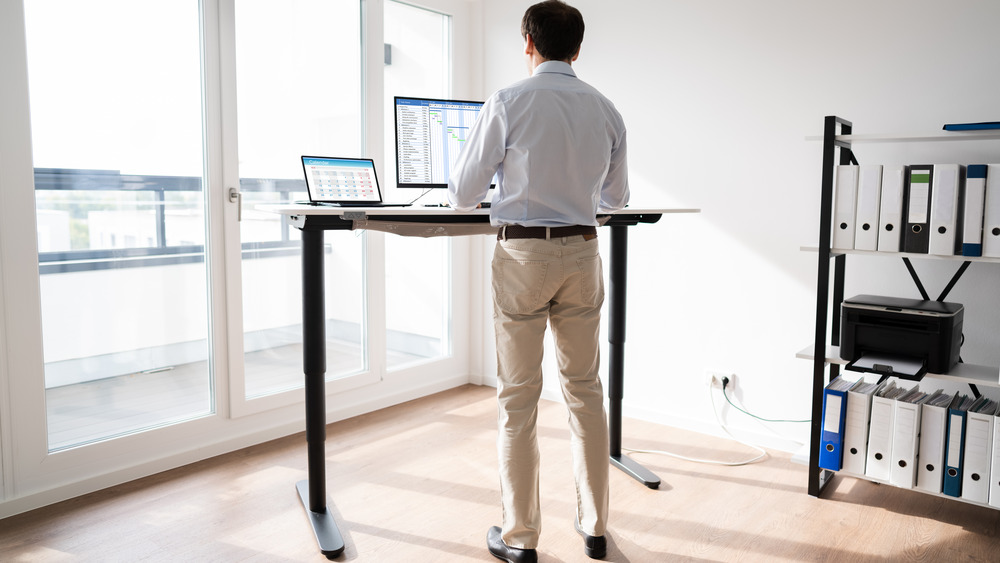 Man working on computer at standing desk in home office