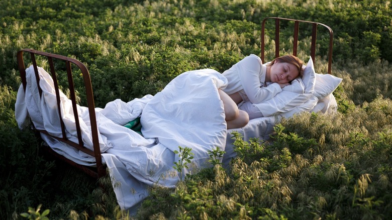 woman sleeping in bed in a field of grass