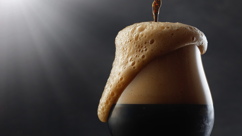 a dark beer overflowing 
