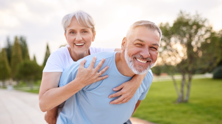 elderly couple enjoying piggyback ride in the park