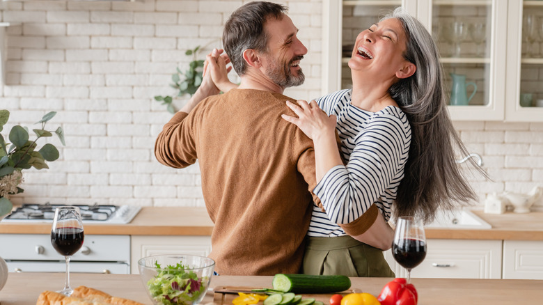 middle-aged couple happily dancing in their kitchen