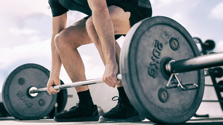 a man squatting down to pick up a barbell