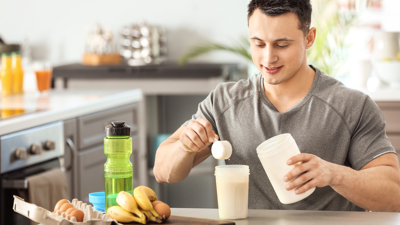 muscular man scooping out protein powder