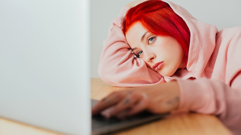 Bored woman working on laptop