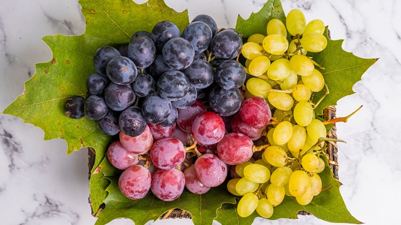 Red, green, and purple grapes on a table
