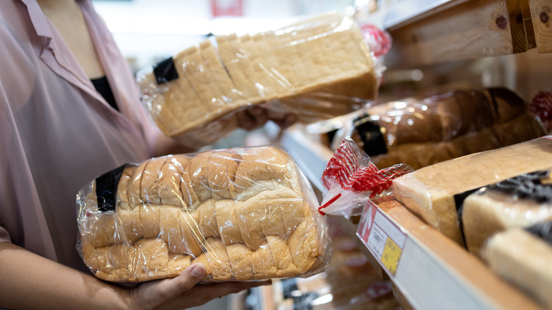 A woman holds two loaves on white bread