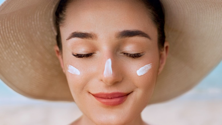 woman in hat with sunscreen on face