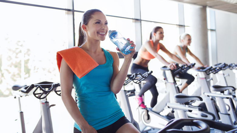 Woman drinking water while indoor cycling