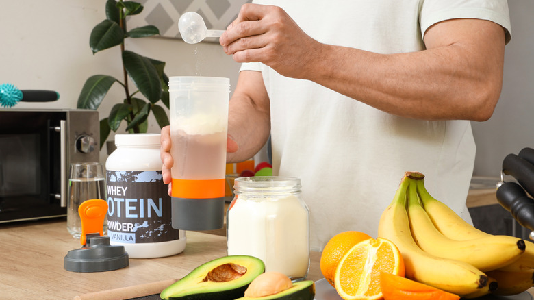 A man scooping protein powder into a bottle