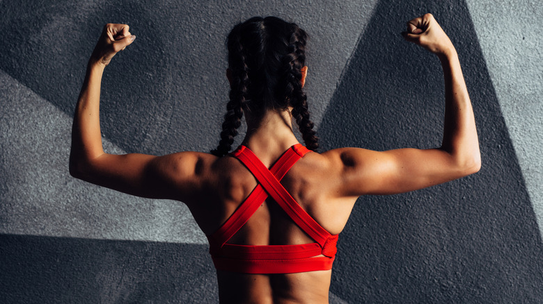 A woman flexing from behind showing muscles