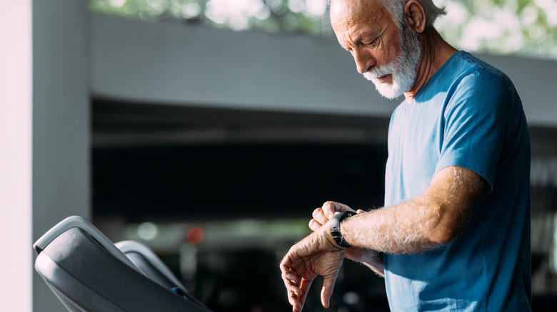 A senior man checking his watch while on a treadmill