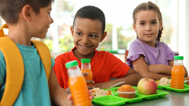 Smiling children eating school lunch