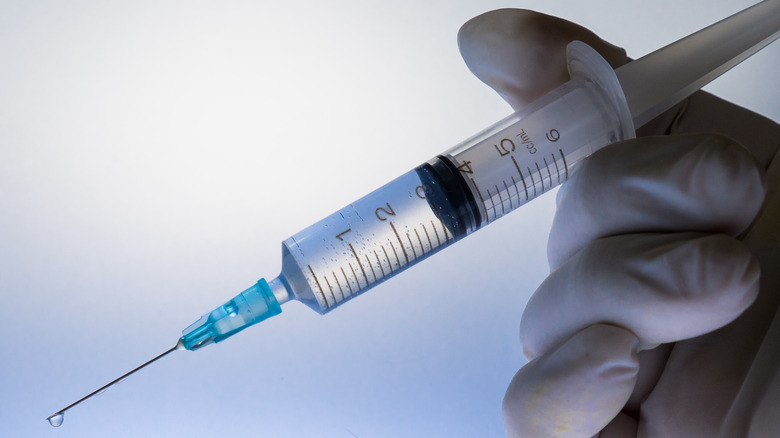 Close up of gloved hand holding a syringe