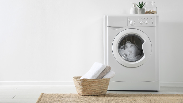 A washing machine with a laundry basket next to it
