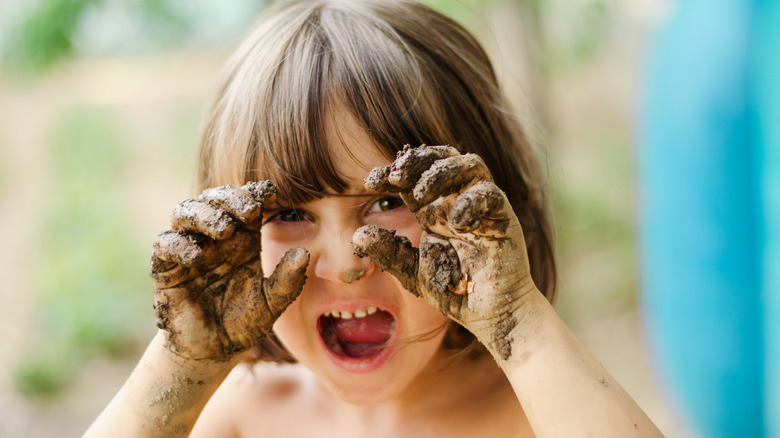 Young boy smiling with muddy hands