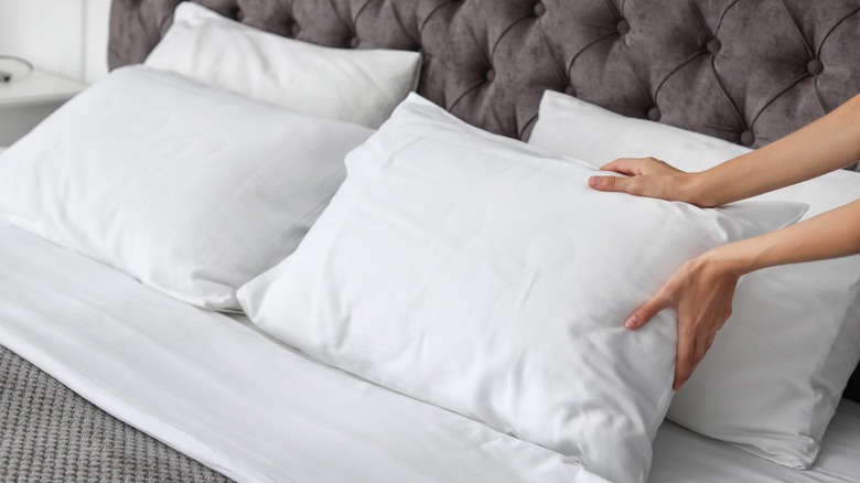 a person fluffing their pillow