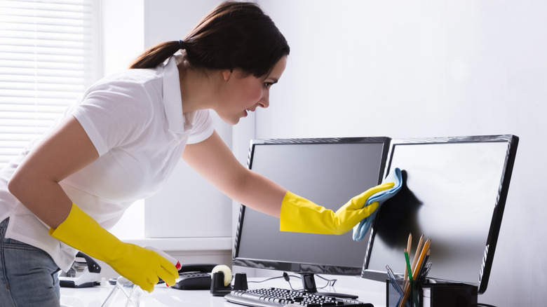 Woman cleaning computer monitor screen