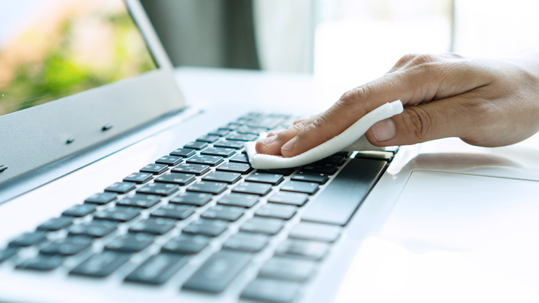 Woman hand cleaning keyboard with disinfectant wet wipe