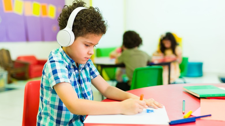 Child drawing wearing headphones