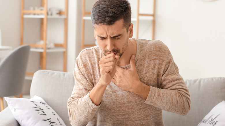 man on couch coughing