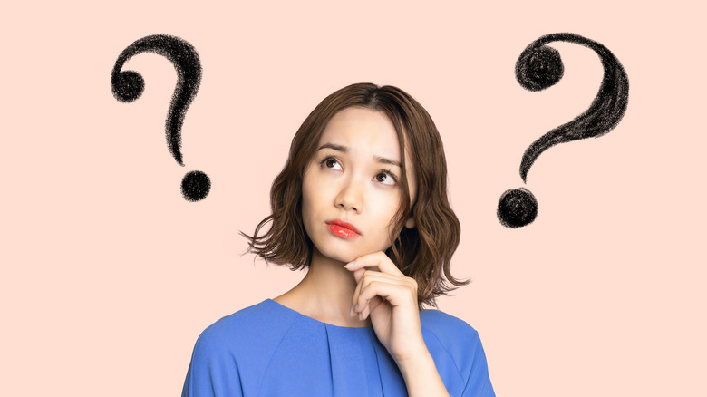young woman wondering with question marks above head