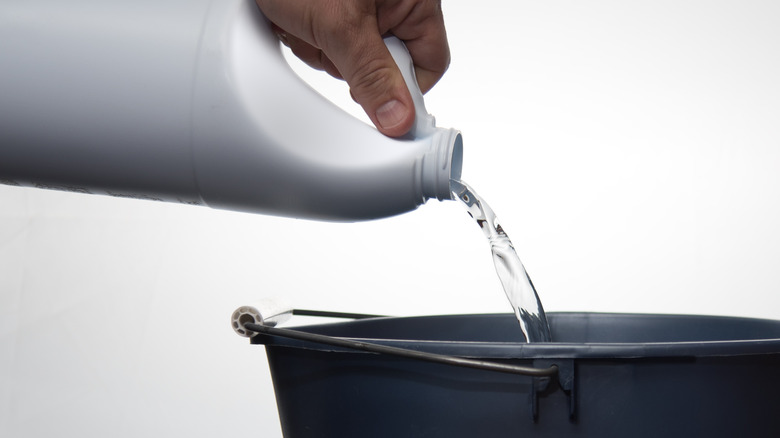 person pouring bleach into a bucket