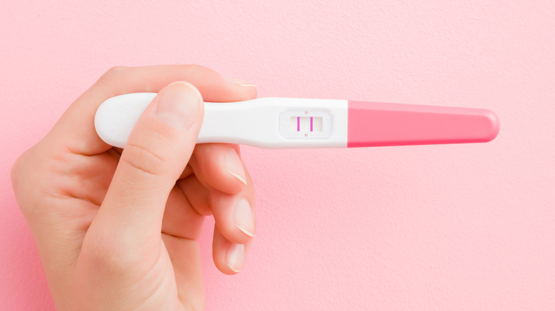 woman holding up a positive pregnancy test 
