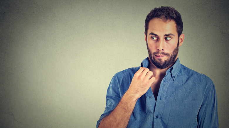 a young man noticing he's giving off an unpleasant odor