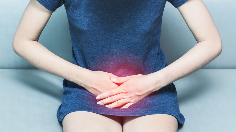 Woman with bladder pain, holding her hands on the pelvic area