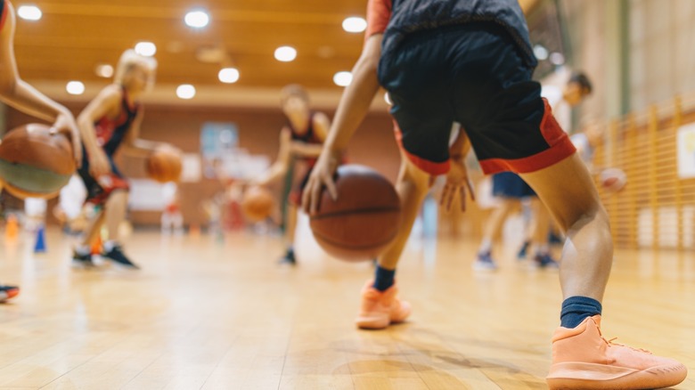 Team of young kids play basketball on an indoor court