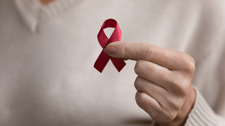 hand holding red AIDS ribbon