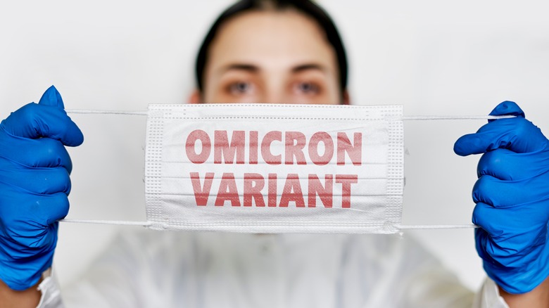 woman holding mask with word "omicron"
