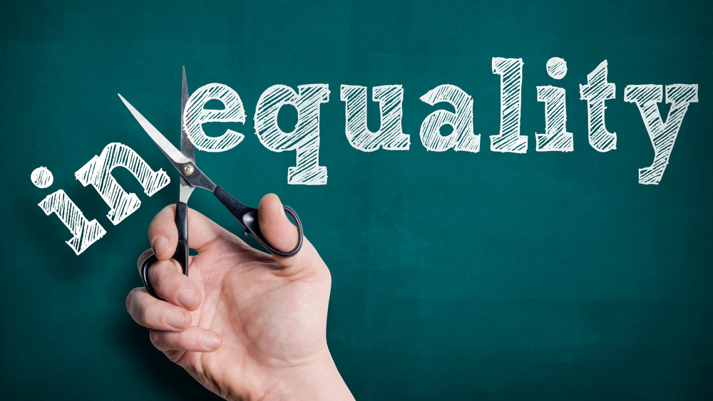 Hand cutting the word inequality with scissors