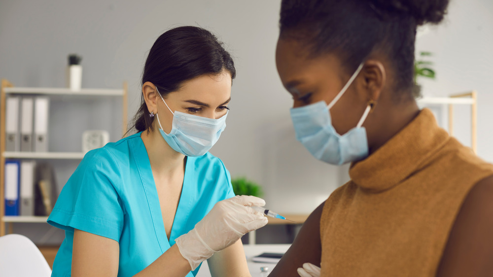 Woman with face mask getting vaccinated against COVID-19