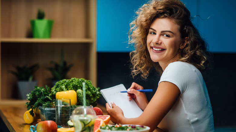 a person taking notes with veggies around them