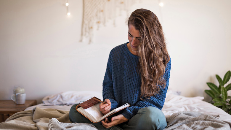 woman sitting on bed journaling