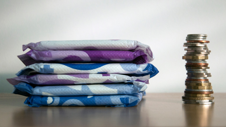 a stack of sanitary pads next to a stack of coins