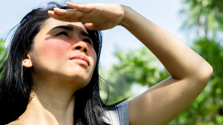 Woman with red cheeks covering face