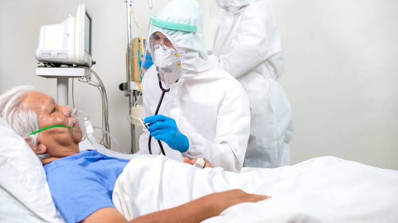 Two doctors running tests on patient in ICU hospital bed