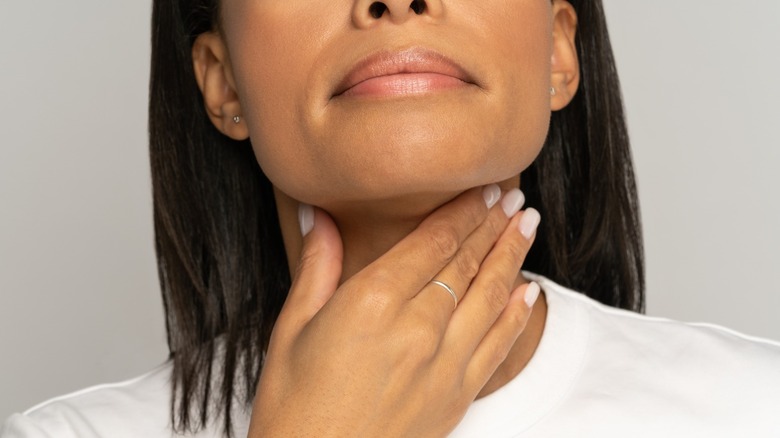 woman touching her thyroid