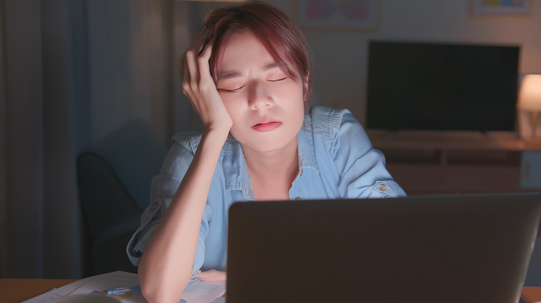 Tired woman falling asleep at desk in front of laptop