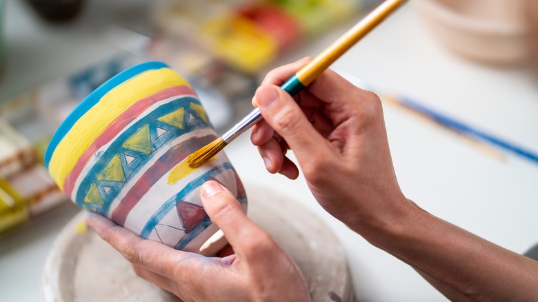 Woman painting a ceramic pot