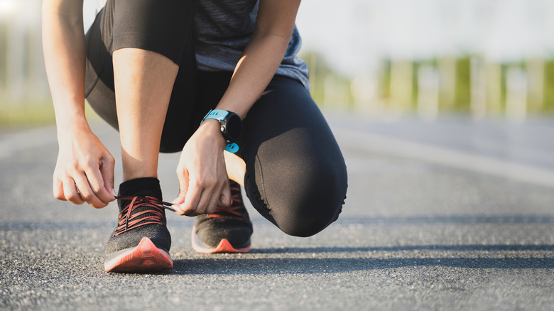 A woman ties her running shoes