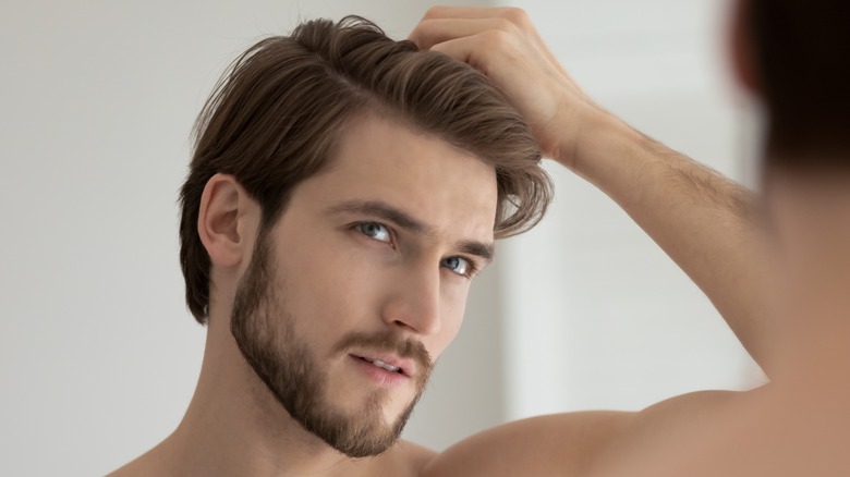 man looking at receding hairline in mirror