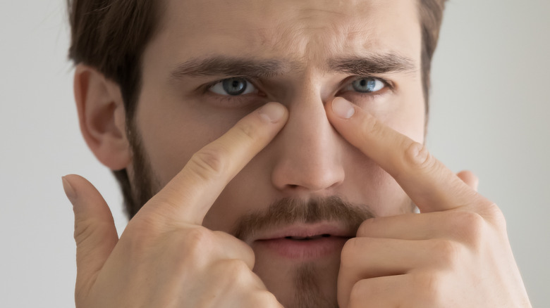 man looking at his eyes in a mirror