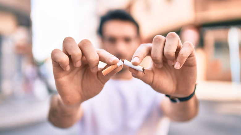 man breaking cigarette in half