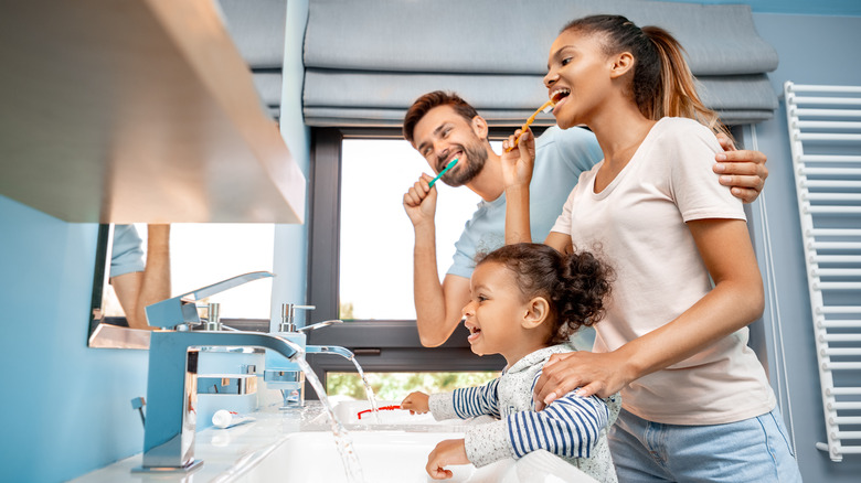 father mother and child brushing teeth