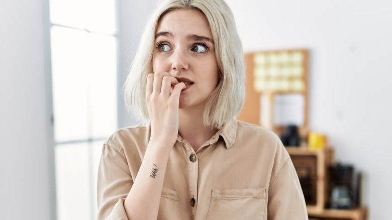young woman biting nails nervously