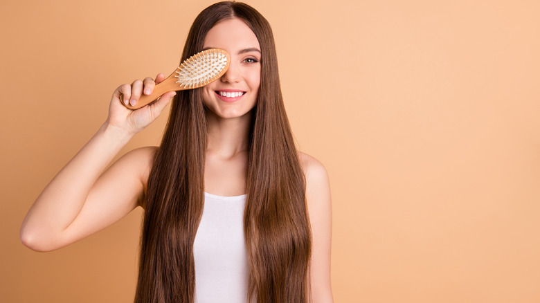 a girl holding a brush and covering her eye