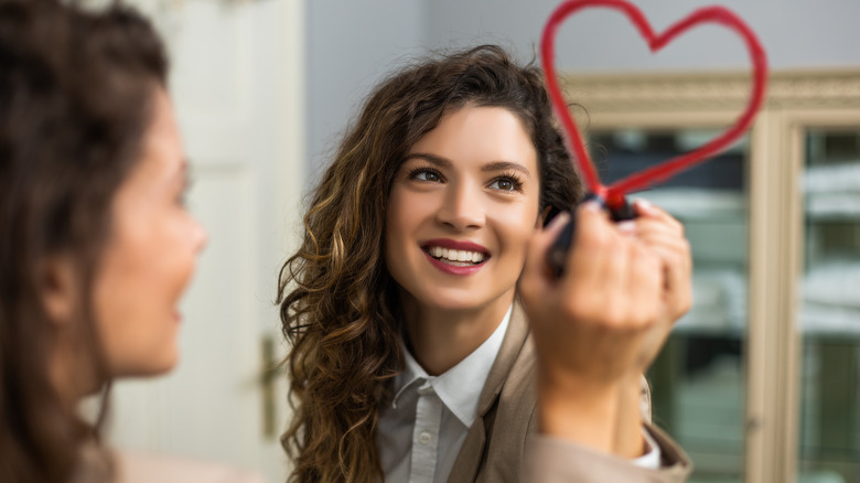 Woman drawing a heart on mirror